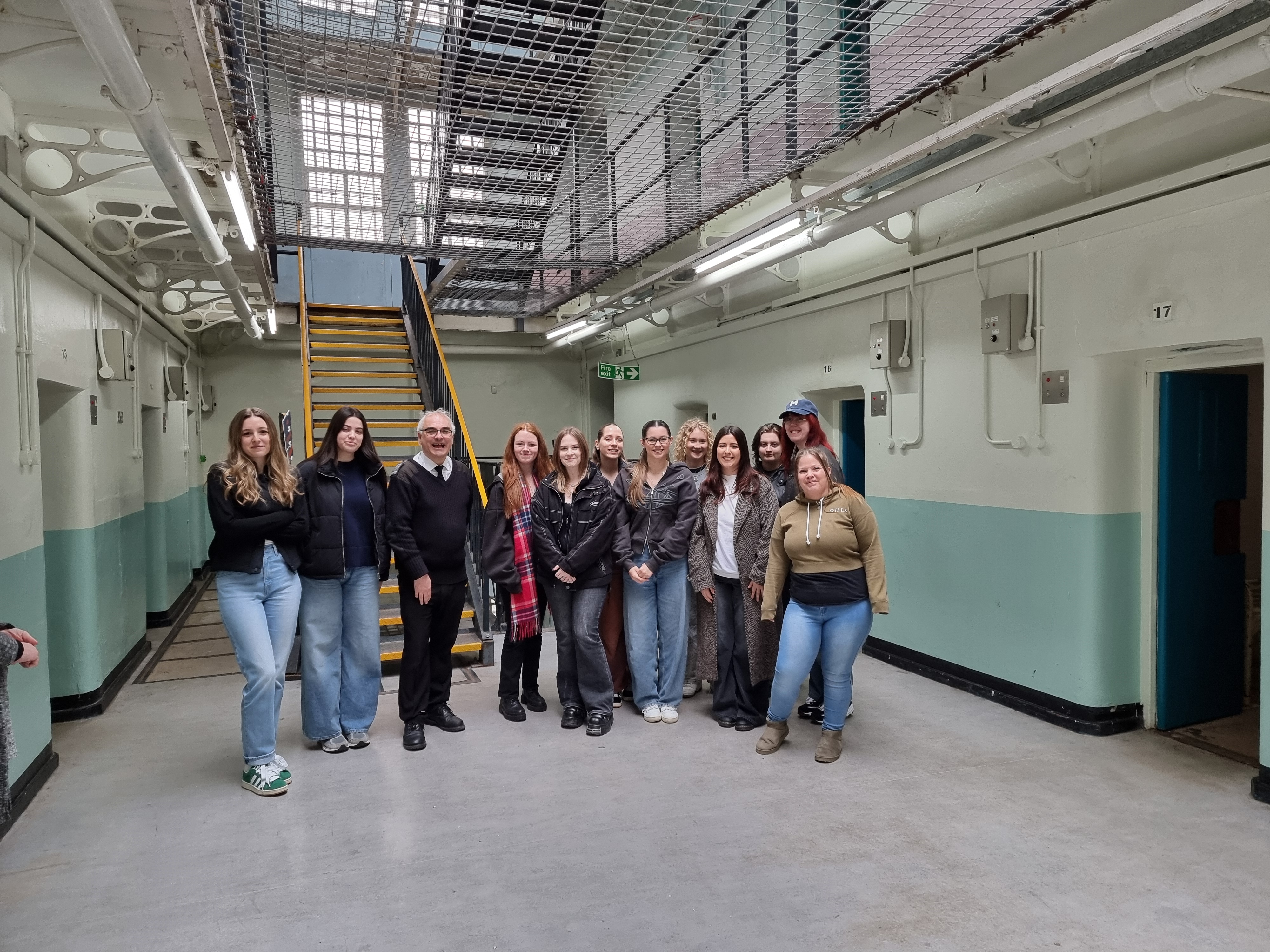 A group of students stand inside a disused prison with a member of staff