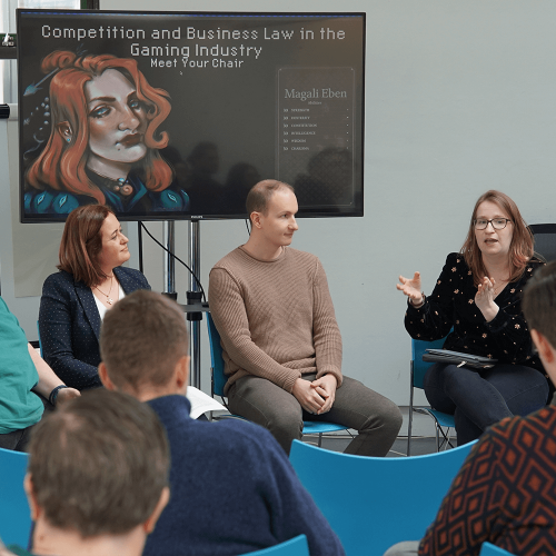 A group of people sat giving a talk in front of a TV screen