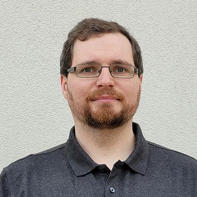 Man in a grey polo shirt with rectangle glasses.