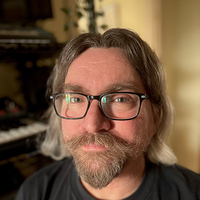 Person with beard and glasses in black t shirt