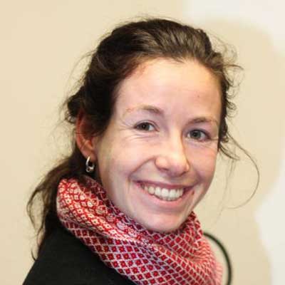 A brown-haired woman wearing a red patterned scarf smiles at the camera