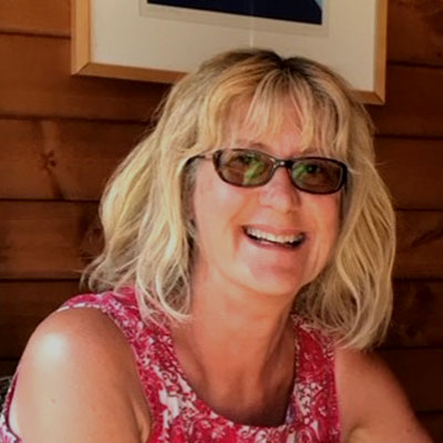 Smiling woman with shoulder-length blonde hair and sunglasses